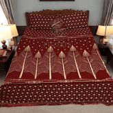 Red and gold patterned bedspread with 'PILORIA' branding on a bed in a room.